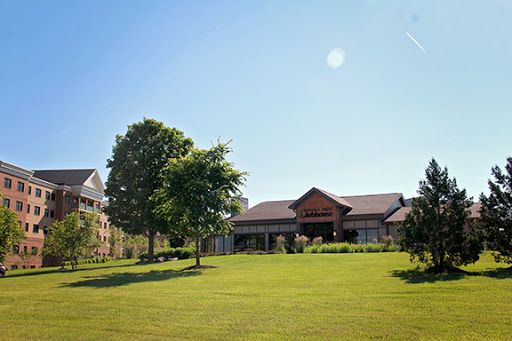 A serene outdoor view featuring a well-maintained building surrounded by lush greenery and a clear blue sky.