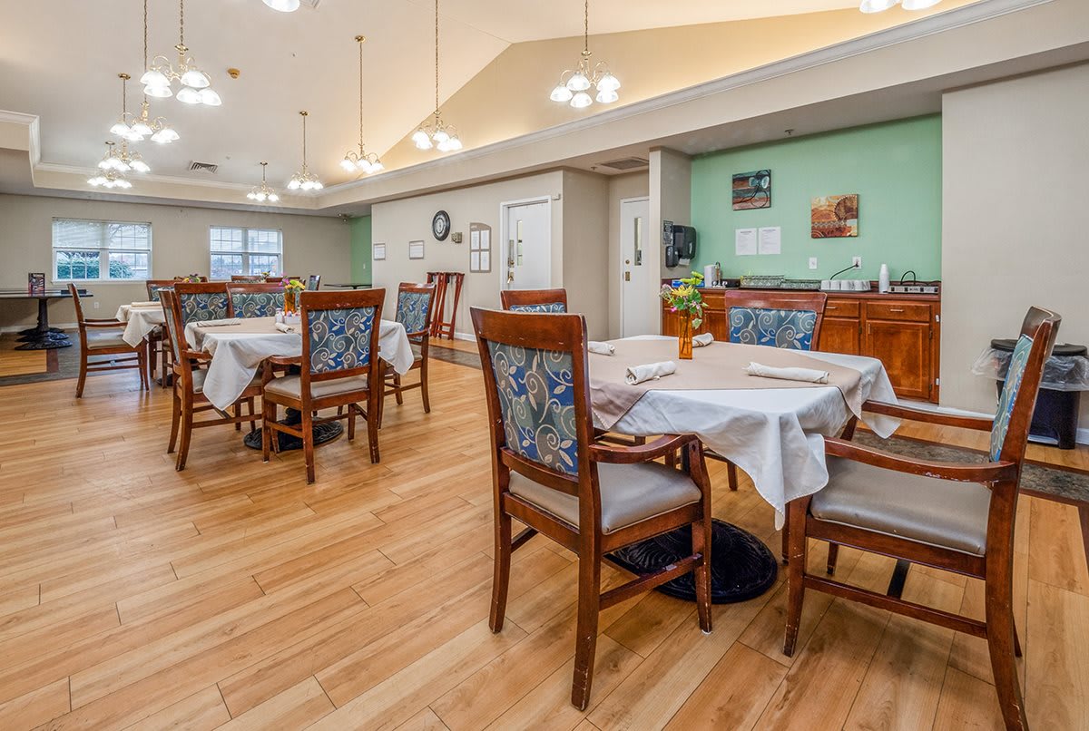 A cozy dining room with wooden floors, featuring tables and chairs arranged neatly.