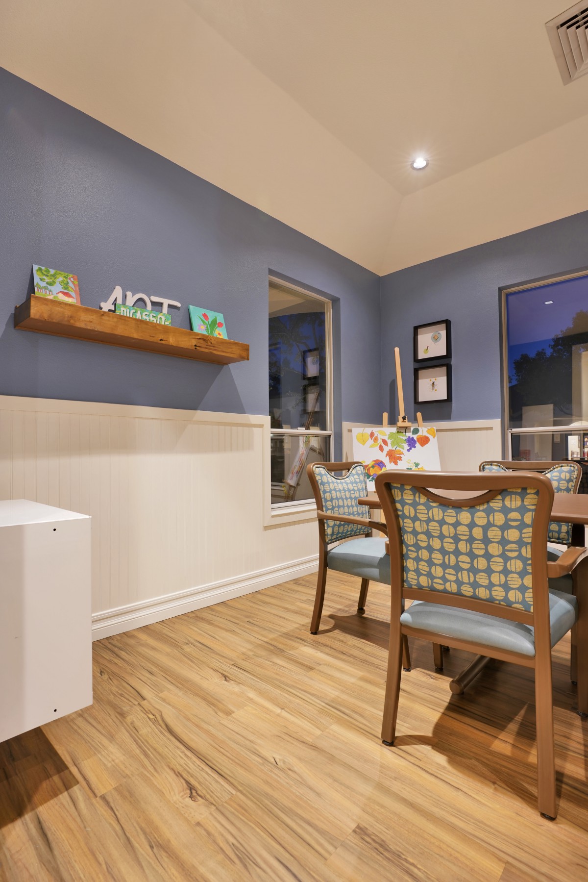 A stylish dining room with blue walls, modern wooden furniture, and decorative artwork creating a cozy atmosphere.