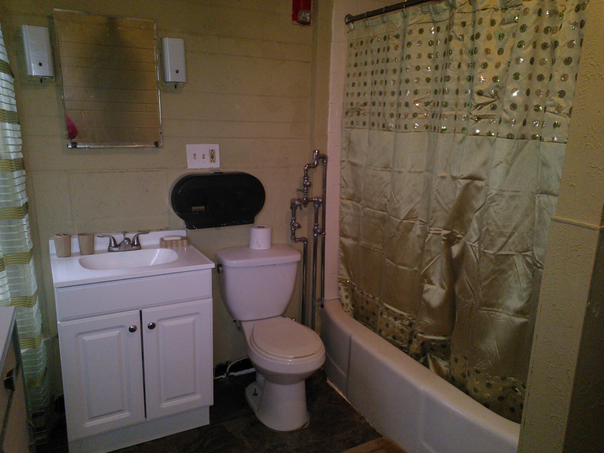 A compact bathroom with a sink, toilet, and shower area.