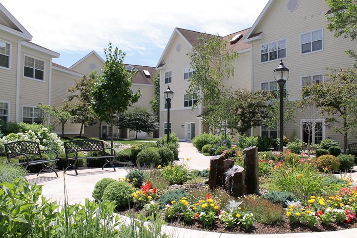 A beautifully landscaped garden with colorful flowers and trees, set in front of a multi-story building.