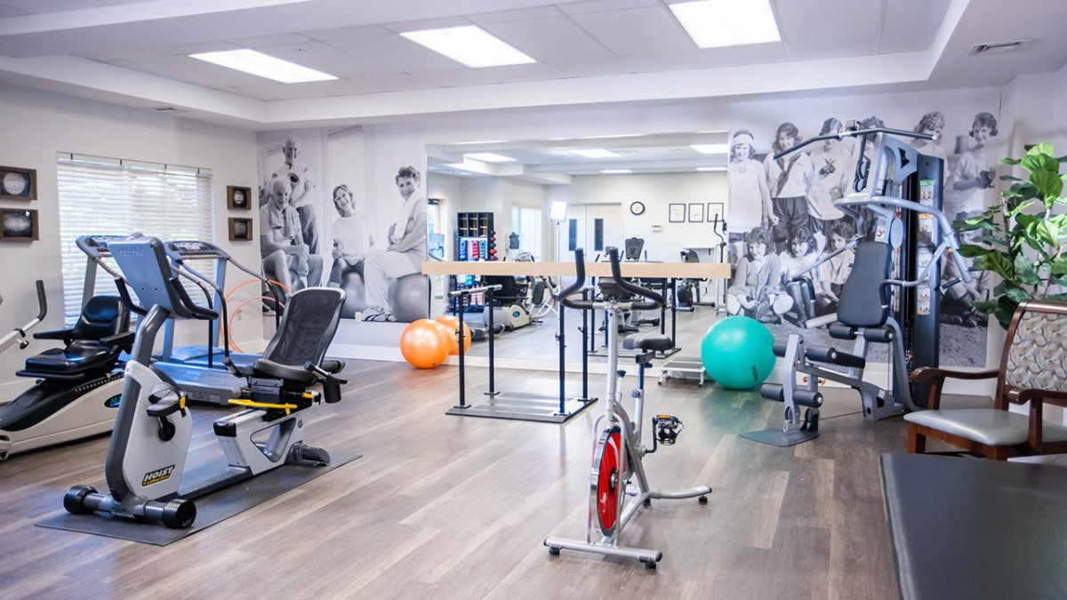 A well-equipped gym with exercise machines and fitness balls, designed for workouts and physical therapy sessions.