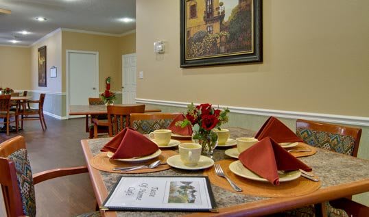 A neatly set dining table with decorative napkins and a floral centerpiece in a cozy room.
