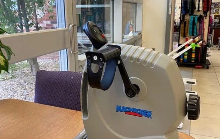 A hand-operated exercise bike on a table indoors.