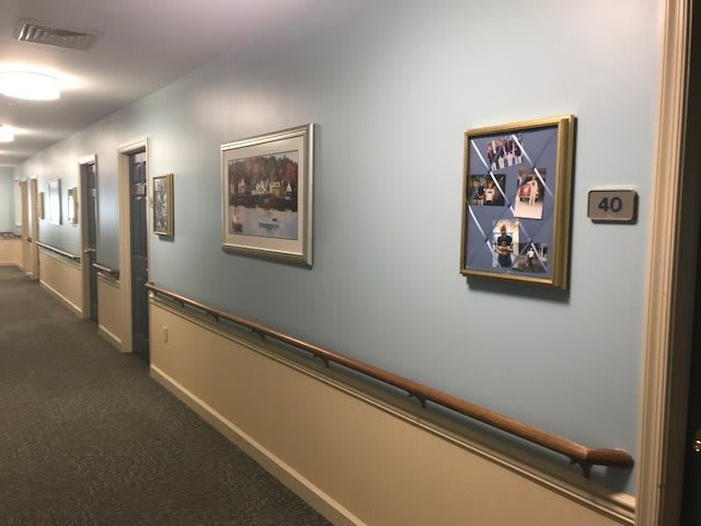 A hallway with blue walls decorated with framed pictures and artwork.