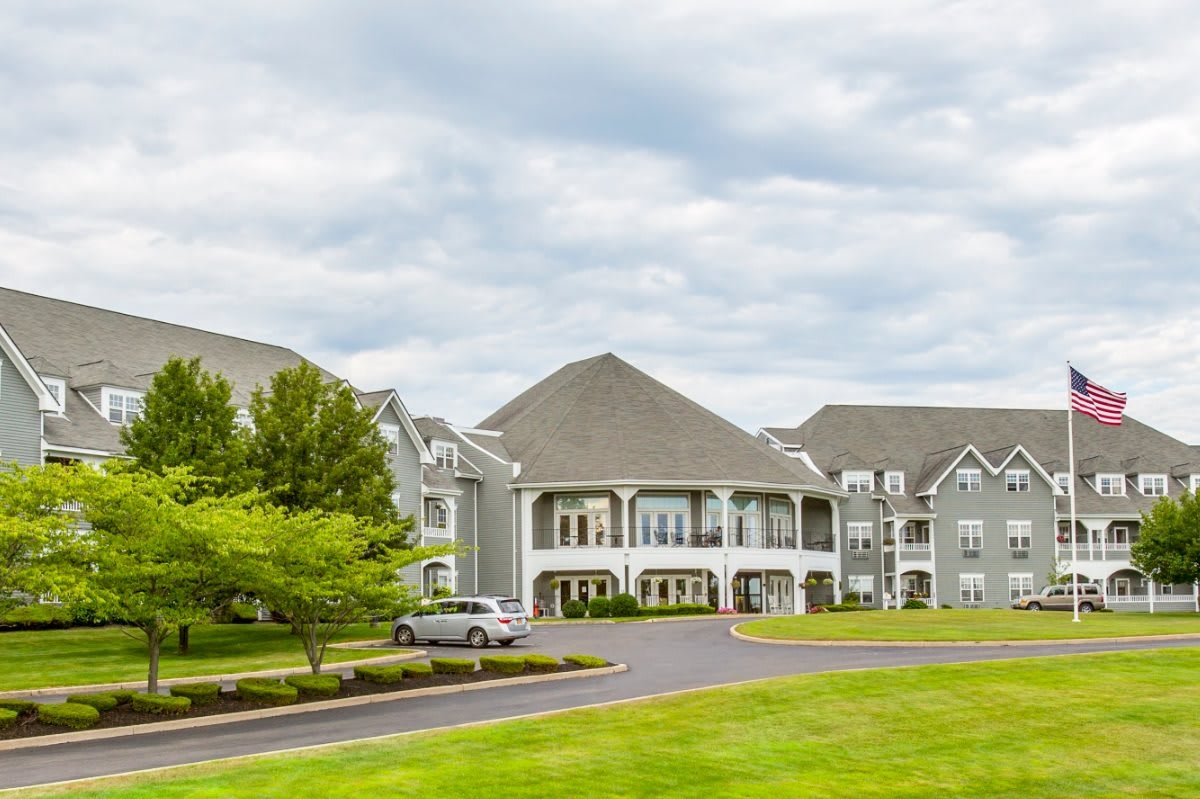 A large residential building surrounded by greenery under a cloudy sky.