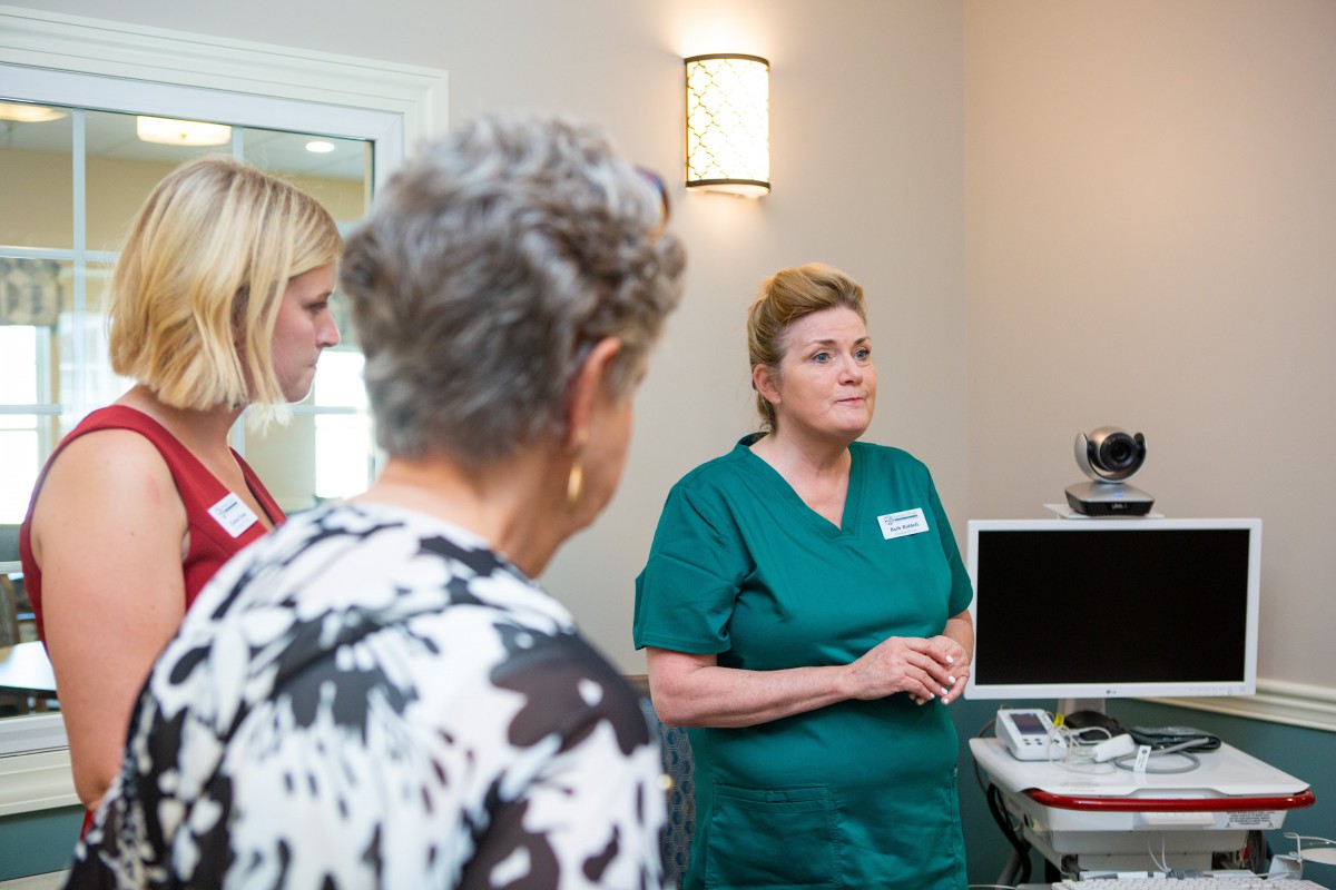 A medical professional in a green uniform consults with patients in a healthcare setting.