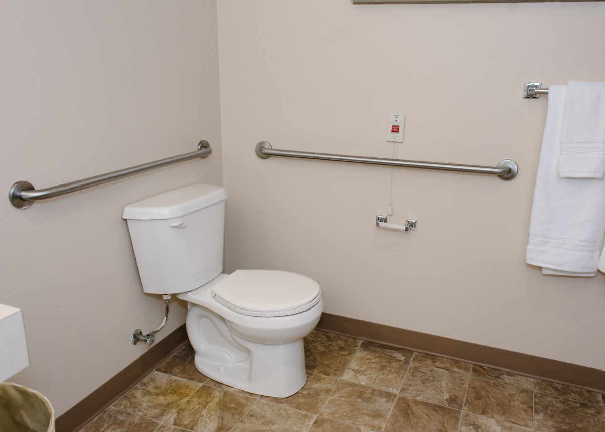 An accessible bathroom featuring a toilet with grab bars for support.