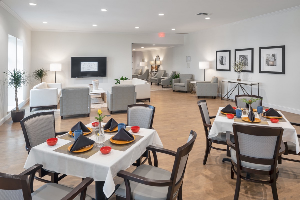 A modern dining and living area featuring elegantly set tables and comfortable seating.