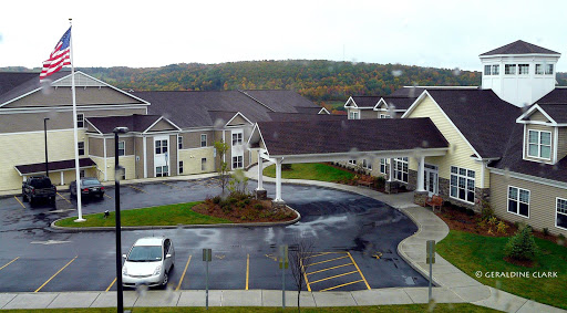 A view of a modern residential building complex surrounded by greenery and a parking area.