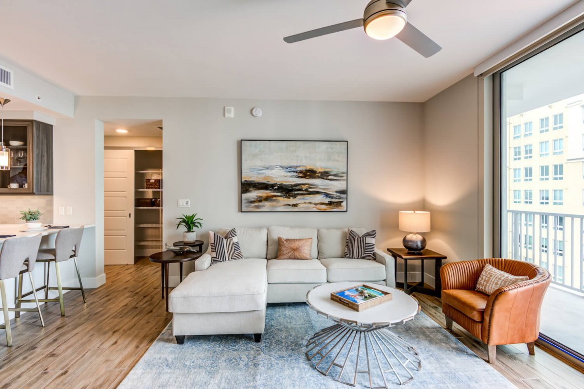 A modern living room with a comfortable sofa, stylish coffee table, artwork on the wall, and a ceiling fan.