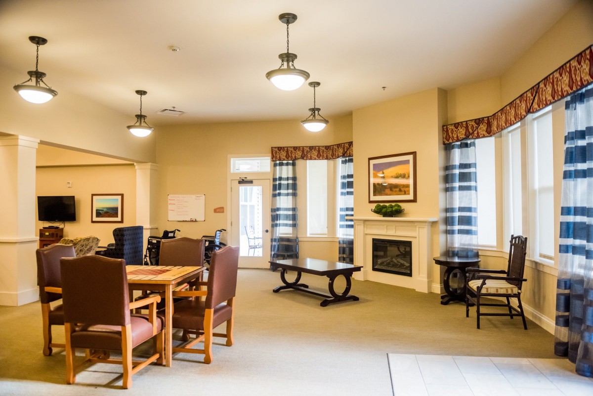 A cozy living room with a dining area, featuring a fireplace, comfortable chairs, and warm lighting.