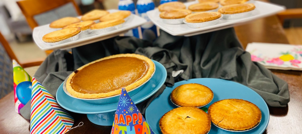 An assortment of pumpkin pies with a festive birthday party hat.