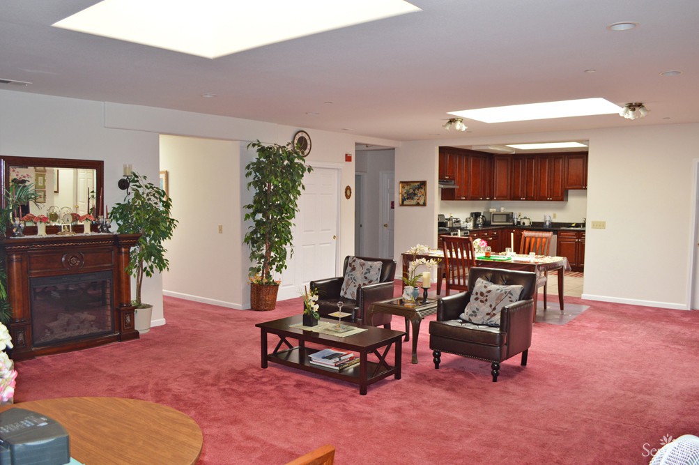 A cozy open floor plan living space featuring a red carpet and adjacent kitchen area.