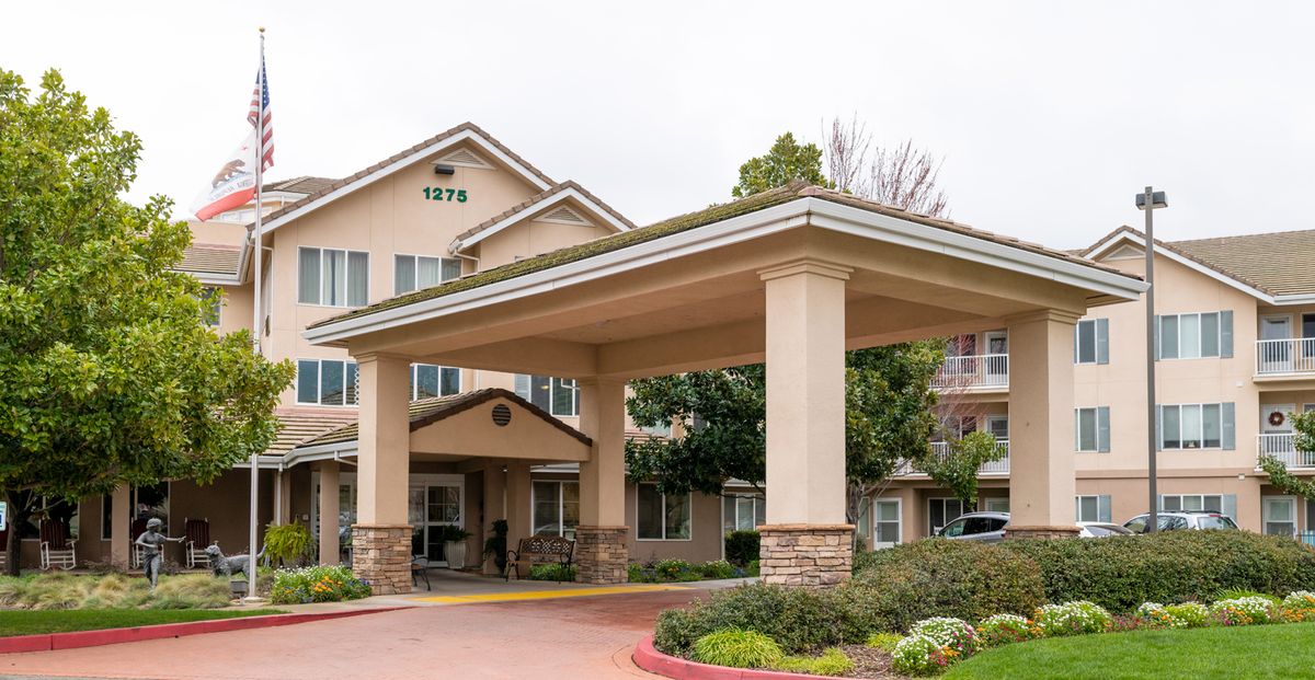 The entrance of a large building with a prominent canopy and landscaped surroundings.