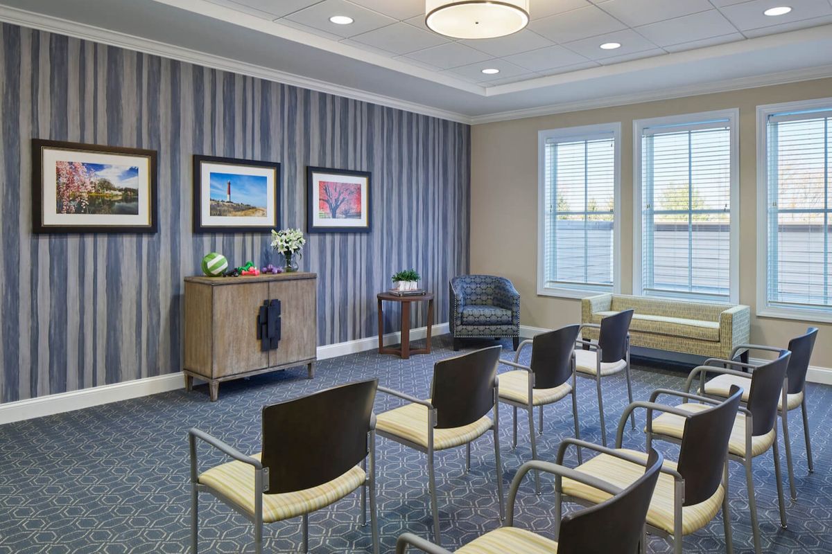 A modern waiting room with several chairs arranged in rows, decorated walls, and framed pictures.