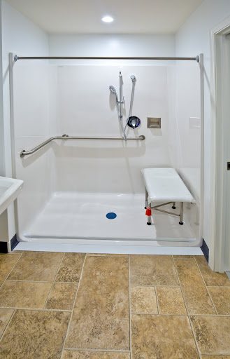 An accessible shower area designed for comfort and safety, featuring grab bars and a bench.
