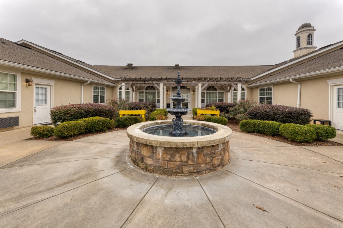 A courtyard featuring a central fountain surrounded by landscaping and a building.