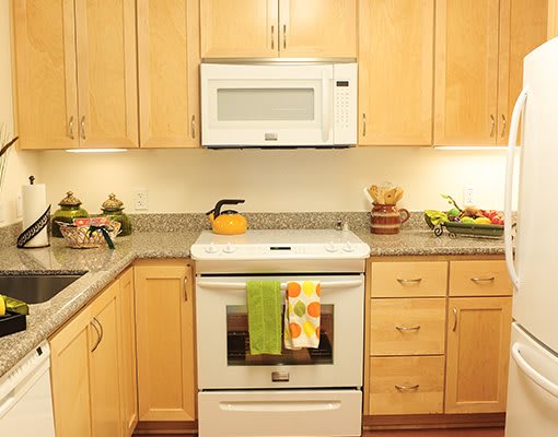 A modern kitchen with wooden cabinets, a stove, and a microwave.