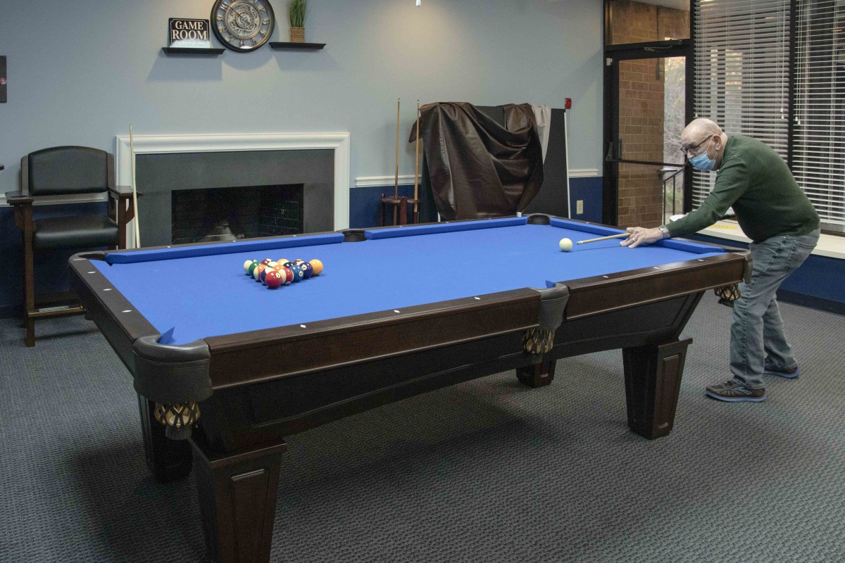 A person playing pool on a blue billiard table in a recreation room.