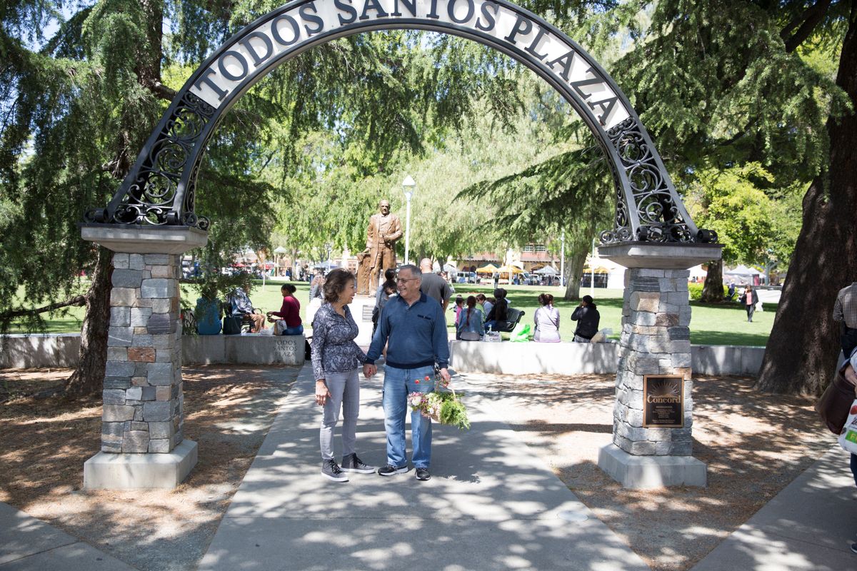 A couple holding hands under the archway at Todos Santos Plaza.