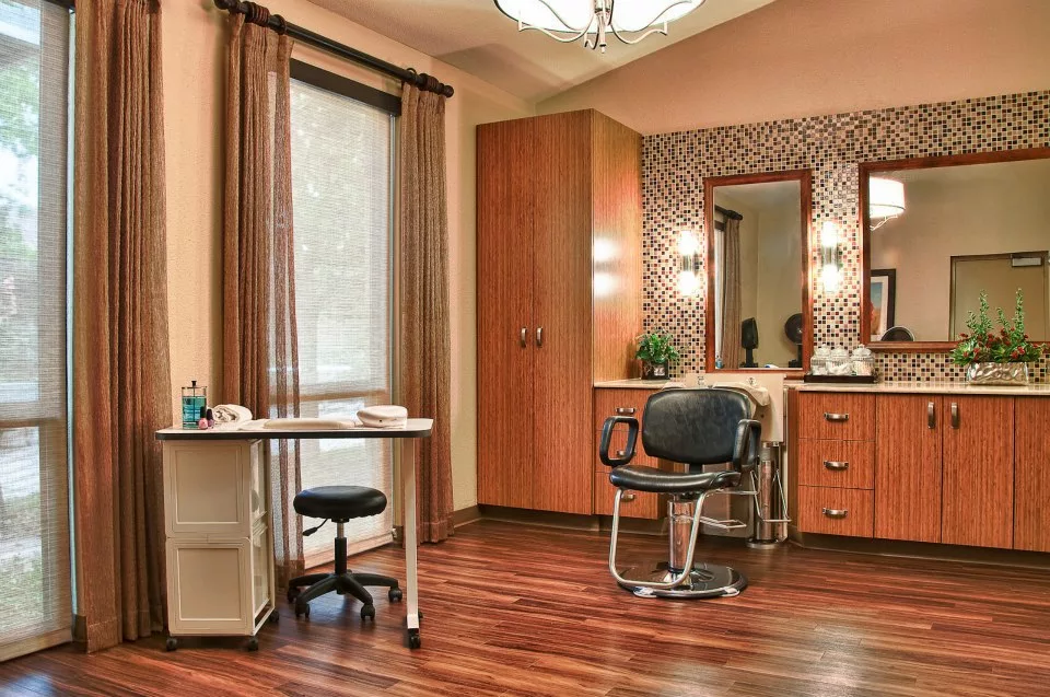 A well-organized hair salon interior featuring a styling chair, mirror, desk, and warm lighting.
