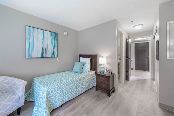 A modern bedroom with a single bed, blue bedding, and minimalist decor.