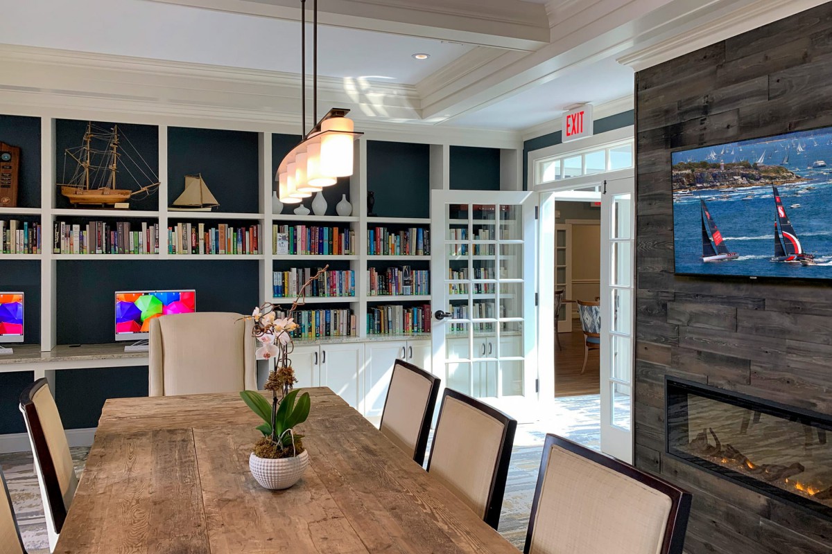A modern dining room with built-in bookshelves, a large table, elegant chairs, and contemporary lighting.