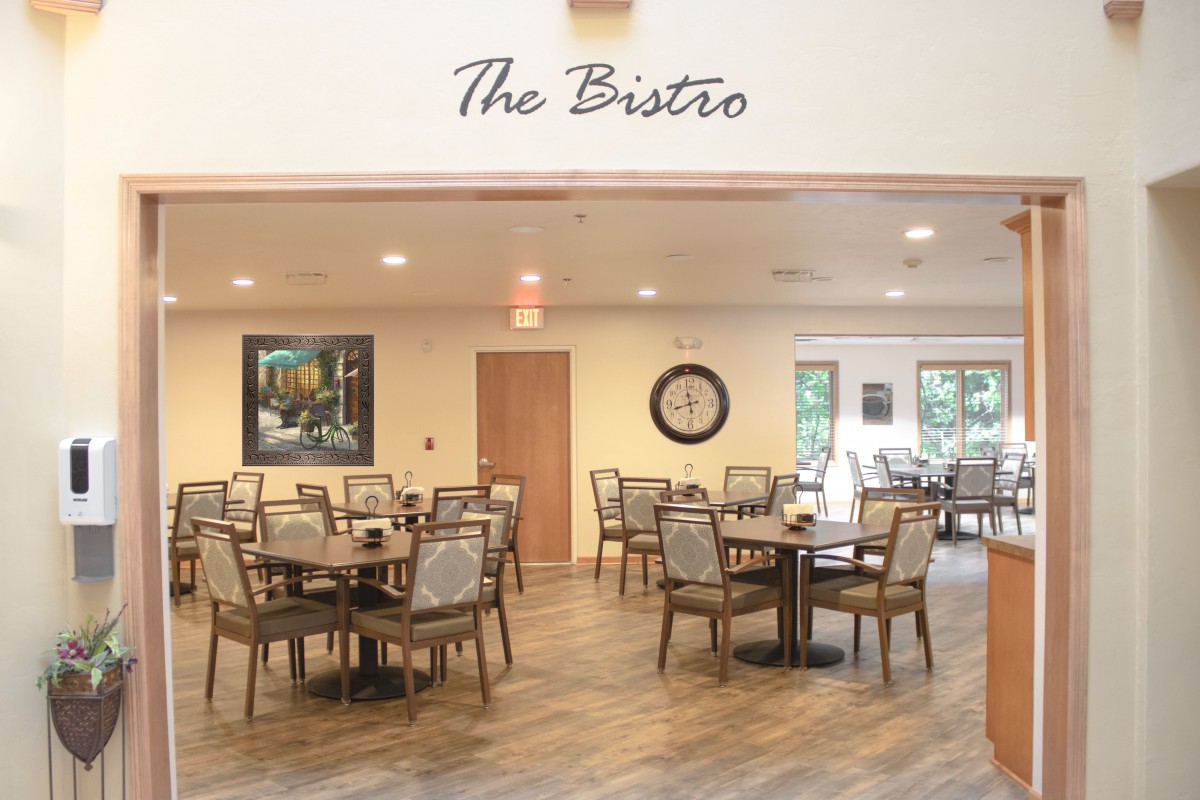 A cozy bistro with neatly arranged tables and chairs, featuring a warm and inviting interior design.