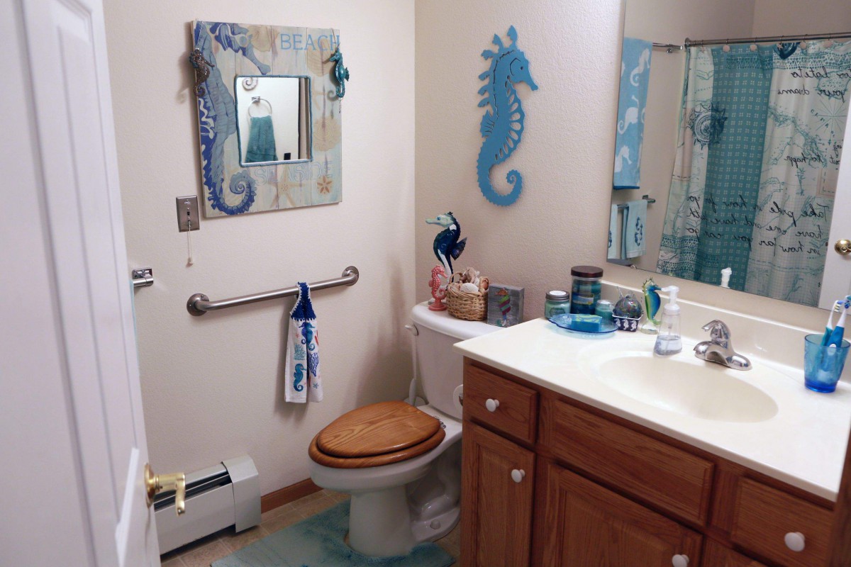 A bathroom with a nautical theme, featuring seahorse decorations and blue accents.