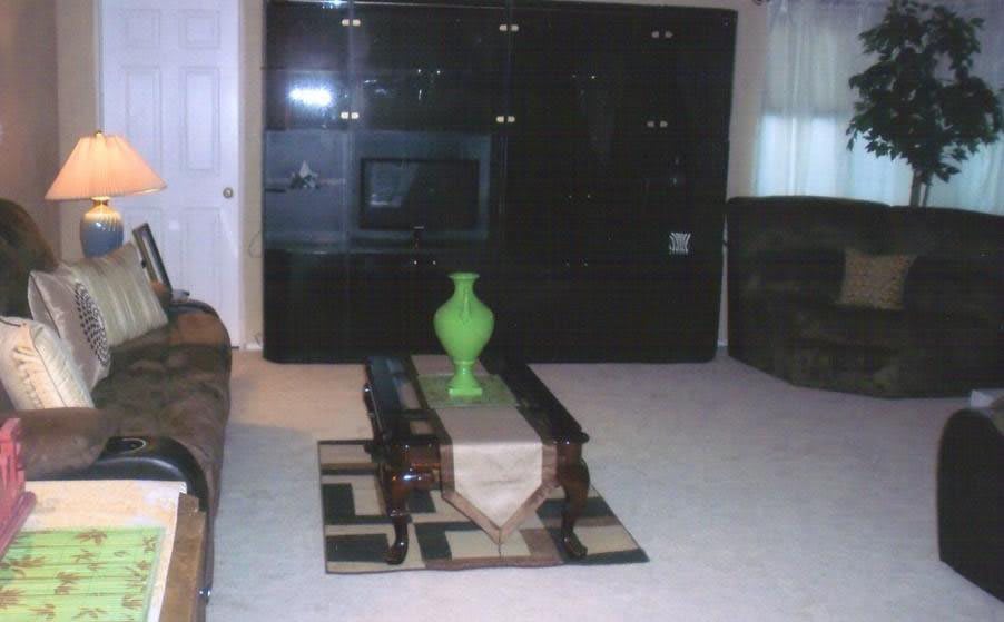 A modern living room with a green vase on a coffee table and an entertainment center.