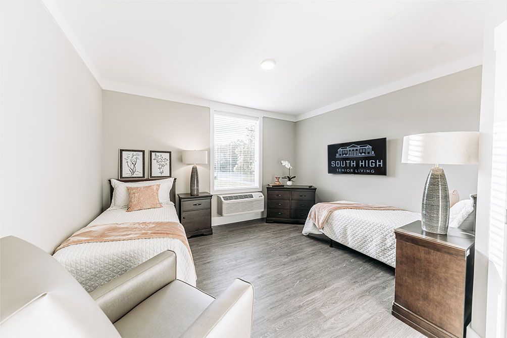 A modern bedroom featuring twin beds, elegant furniture, and wooden flooring.