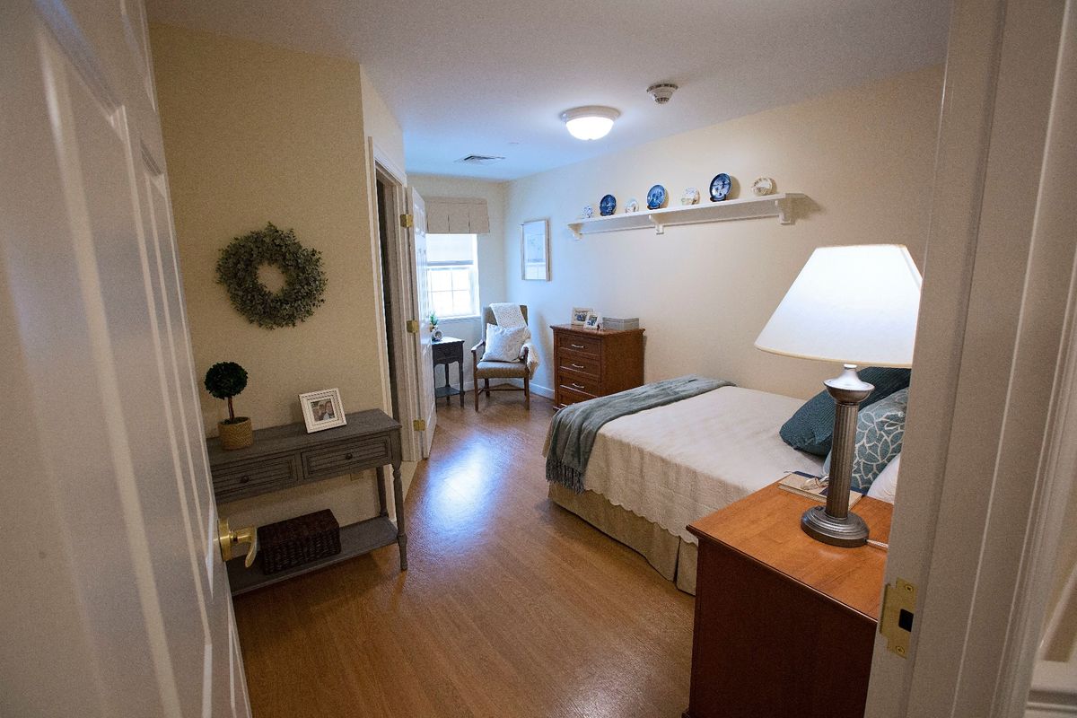 A cozy and well-decorated bedroom featuring a bed, lamp, and a wall shelf with decor.