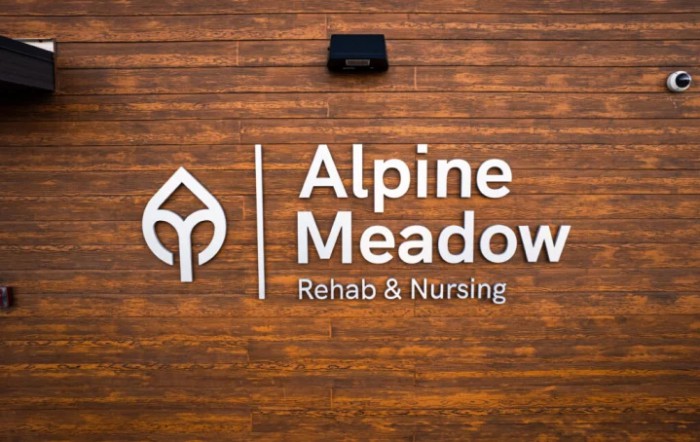 Sign for Alpine Meadow Rehab & Nursing facility on a wooden background.