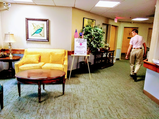 A well-lit lobby area featuring a yellow couch, decorative artwork, and a person walking down the hallway.