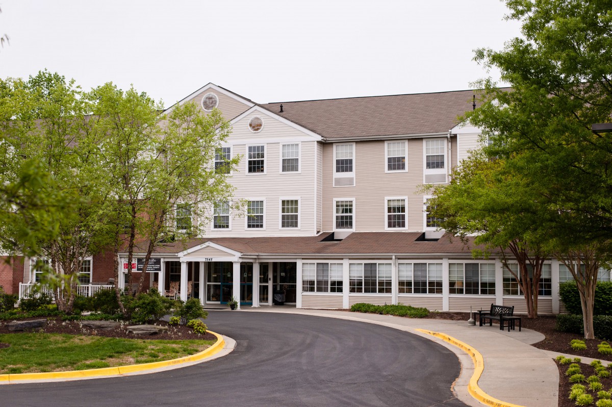 Front view of a hotel building with a driveway and trees.