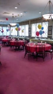 A decorated room with tables and colorful balloons, ready for a party or event.