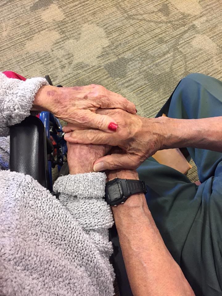 Elderly couple holding hands, symbolizing love and companionship.