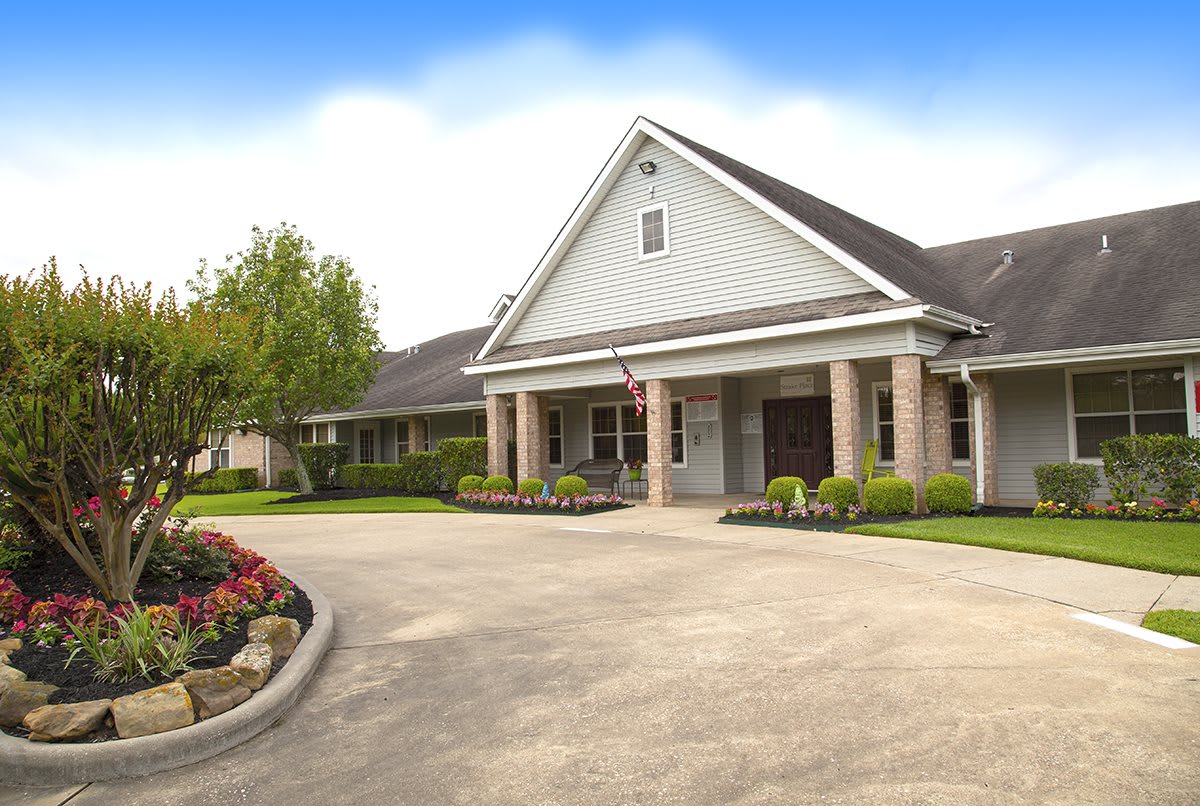 A well-maintained building with a landscaped entrance and driveway under a blue sky.