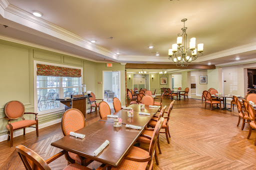 A cozy dining area featuring a wooden table surrounded by upholstered chairs, illuminated by a stylish chandelier.