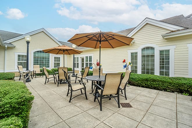 A well-maintained patio area with tables, chairs, and umbrellas outside a building.
