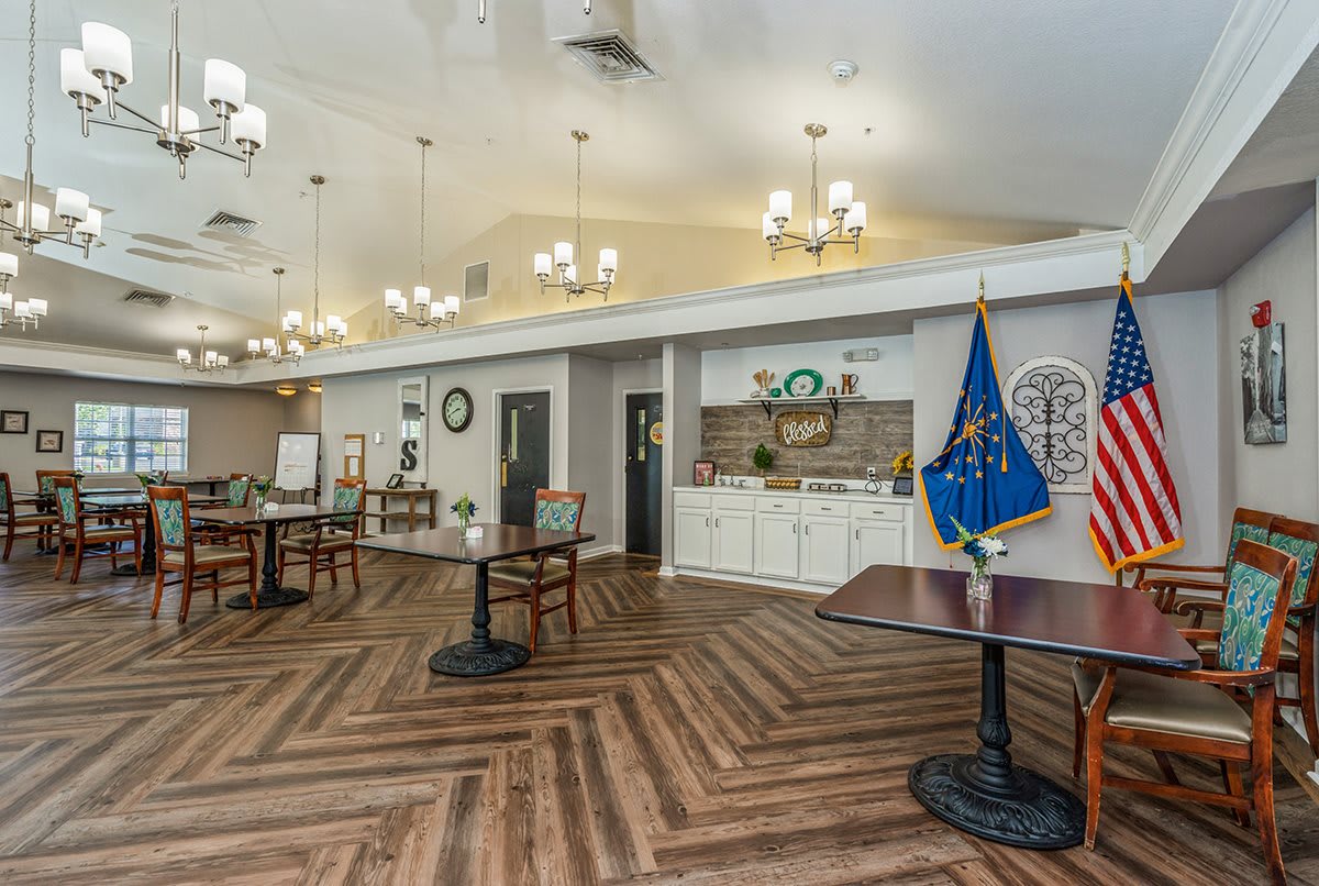 A spacious dining area featuring elegant chandeliers, hardwood flooring, and decorative flags.