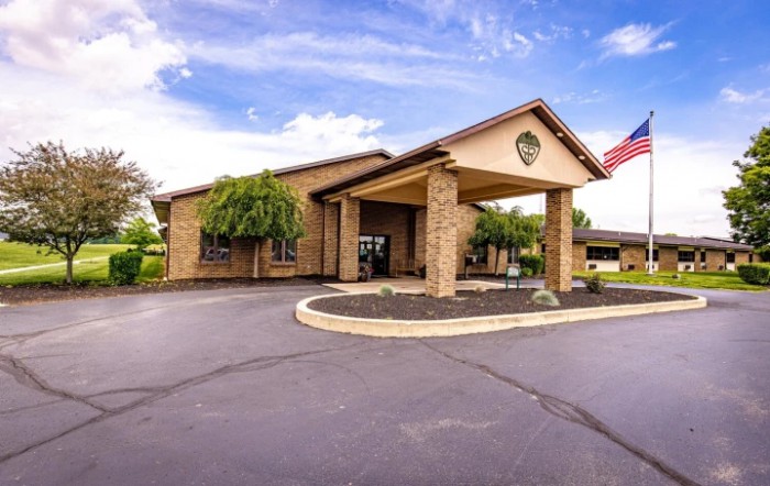 A well-maintained building with a covered entrance and surrounding landscaping on a sunny day.