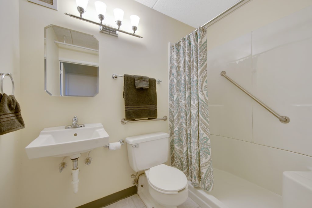 A clean and well-lit bathroom with a sink, toilet, and shower area.