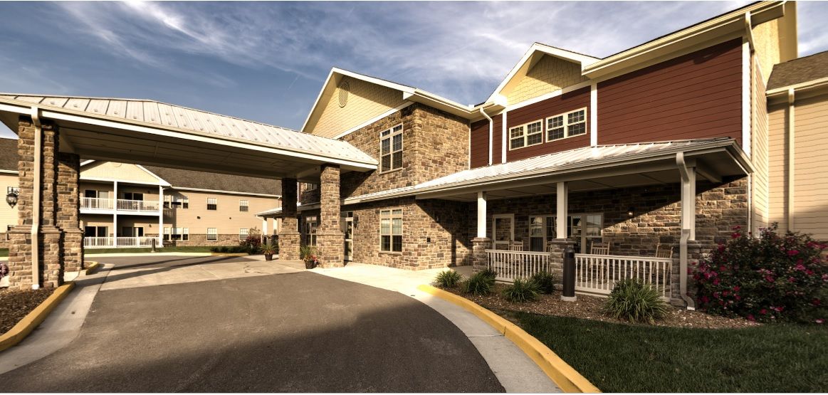 A modern residential building featuring a stone facade and covered driveway.