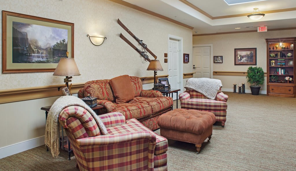 A cozy living room with plaid furniture and decorative skis on the wall.