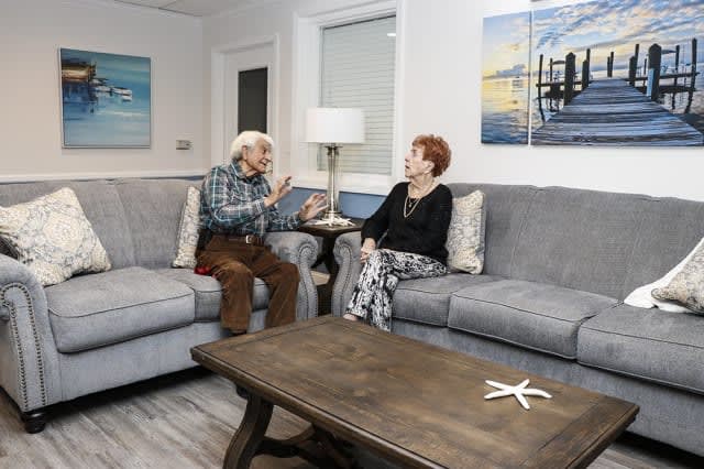 An elderly couple having a conversation in a cozy living room setting.