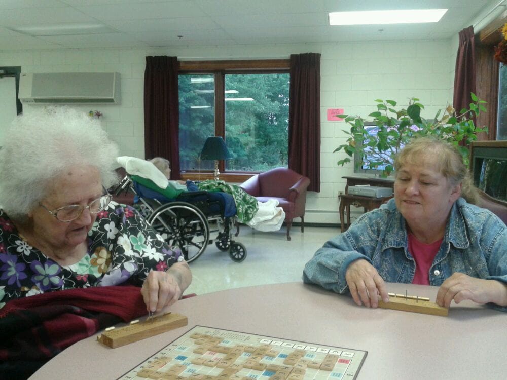 Two elderly women enjoying a game together indoors.