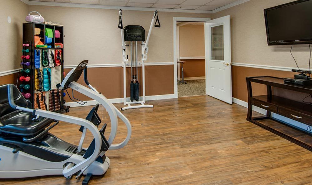 A small gym with exercise equipment and wooden flooring.