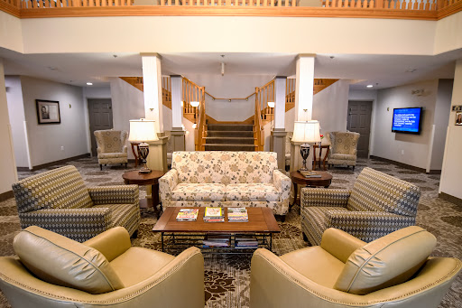 A cozy hotel lobby featuring a floral-patterned sofa, comfortable armchairs, and a welcoming atmosphere.